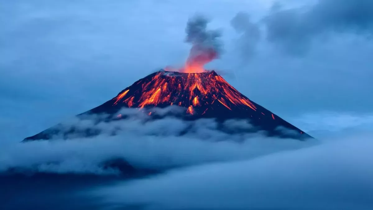 Erupting volcano over sea of clouds